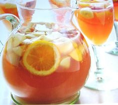 a pitcher filled with fruit and ice next to two glasses