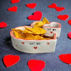 a bowl filled with chips sitting on top of a table covered in heart shaped confetti