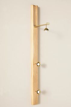 a wall mounted coat rack with three brass knobs