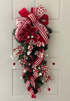 a red and white christmas wreath hanging on the front door