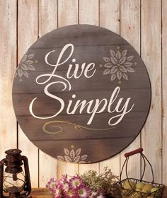 a wooden sign that says live simply on it next to some flowers and other items