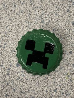 a green sticker with a black pixel on it's face sitting on the ground