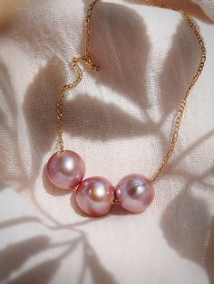 *Limited Edition* An unfailing new classic. This Triple Edison Floating Pearl Necklace is a steadfast companion. Seemingly plucked straight from the ocean, three near round pink pearls flutter along a delicate gold filled chain. This piece is striking solo or makes a bold statement layered with with a bevy of other beauties. ✦ CHOOSE YOUR ADJUSTABLE LENGTH ✦ ✦ DETAILS ✦ ✧ Name: Lokelani (LOE keh LAH nee) - heavenly rose. ✧ Three Large 12mm-13mm Natural Mauve Edison Pearl ✧ Color will vary slight Elegant Pink Pearl Drop Necklace, Elegant Pink Pearl Charm Jewelry, Elegant Pink Pearl Necklace With Pendant, Luxury Single Strand Pink Jewelry, Luxury Pink Round Beads Jewelry, Luxury Pink Single Strand Jewelry, Pink Pearl Necklace With High Luster, Luxury Pink Necklace With Pearl Pendant, Pink Akoya Pearl Single Strand Necklace