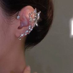 The image provided is not of a garment but rather shows an ear cuff or earring on a person's ear. Here is a description of the earring shown: Material: Metallic, shiny crystals Color: Silver, translucent gems Design: Floral, cascading jewels Style: Ear cuff, statement piece Occasions: Formal events, celebrations Styling: Elegant updo, evening dress Ear Cuffs No Piercing, Wedding Ring Hand, Ear Piece, Non Pierced Earrings, Ear Pieces, Couples Accessories, Prom Accessories, Wrap Earrings, Ear Jacket