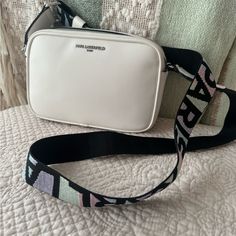 Karl Lagerfeld Maybelle Bag With Colorful Strap. Perfect For The Summer. Double Top Zipper Closure Exterior: 1 Back Slip Pocket Interior: 1 Slip Pocket, 3 Card Slits Adjustable Crossbody Strap 14" - 23" Strap Drop 9" W X 6" H X 3" D Spot Clean Imported Style Number: Lh0er9bj Modern White Shoulder Bag With Logo Strap, White Bag With Logo Strap For Everyday Use, White Bags With Logo Strap For Everyday Use, Luxury White Shoulder Bag With Logo Strap, White Shoulder Bag With Logo Strap For Travel, White Crossbody Bag With Logo Strap, Chic White Shoulder Bag With Logo Strap, White Crossbody Shoulder Bag With Long Strap, Chic White Bag With Logo Strap