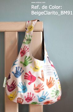 a purse with hand prints on it hanging from the side of a wooden rack in front of a blue wall