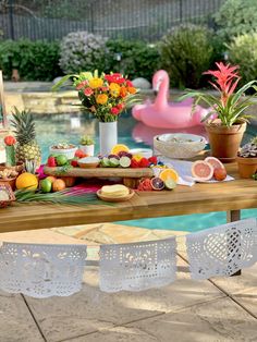 tropical fiesta taco bar with flowers and fruit on the table next to an inflatable flamingo