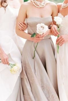 three bridesmaids pose for a photo in their wedding gowns and bouquets