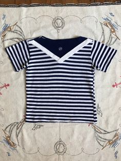 "RARE 1950s striped t-shirt with an embroidered boat wheel in navy blue and white stripes. I do think this is a juniors t-shirt but will fit a small adult.  Label: none  Measurements: { xxsmall } Pit to Pit: 14.5\"-18.5\" Length: 17\" Sleeve Length: 5.5\" Armhole is about 13\" around approx.  Condition: fabric is worn as shown in photos but still totally wearable and presents well. washed and ready to wear - sold as found. Shop more: www.trunkofdresses.com" Cheap Nautical Style Short Sleeve T-shirt, Blue Nautical Style T-shirt For Summer, Marine Style Cotton Crew Neck Top, Navy Marine Style Cotton Top, Navy Cotton Marine Style Tops, Navy Sailor Crew Neck Top, Navy Cotton Nautical Tops, Nautical Crew Neck T-shirt For Boating, Sailor Style Cotton Crew Neck Top