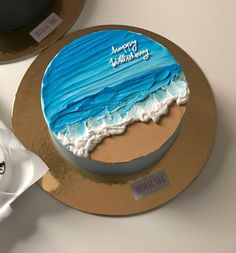 a blue and white birthday cake sitting on top of a table next to a cup