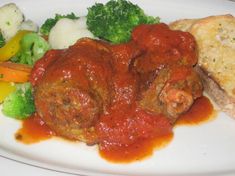 meatballs, broccoli and carrots are on a white plate with red sauce