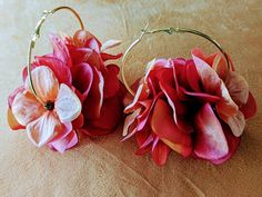 two flowered hoop earrings sitting on top of a bed