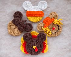 three crocheted mickey mouse and donald duck appliques on a white surface