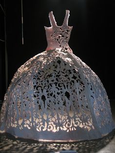 a dress made out of paper sitting on top of a metal stand in the dark