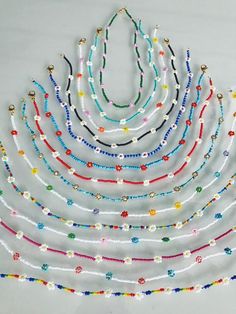 multicolored beaded necklaces are arranged on a white surface with beads in the shape of a triangle