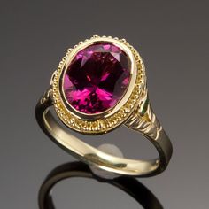 Exquisitely handcrafted in granulated 18KY gold, the “flower” of this one-of-a-kind ring is a 3.13ct rubellite tourmaline. Butterflies created in 18KW and each set with a 1.3mm VS/GH diamond are found on either side of the center gemstone. 2mm tsavorite garnets and the engraved leaf pattern create the flower’s stalk on the shank as engraved butterflies on the shank and beneath the center stone all flutter to the dazzling raspberry-red of the luscious rubellite tourmaline. Size 5.5, but each ring Formal Yellow Gold Emerald Ring, Formal Ruby Ring With Tourmaline Accents, Yellow Gold Ruby Ring With Tourmaline Center Stone, Elegant Ruby Birthstone Ring With Tourmaline, Vine Engagement Ring, Rubellite Tourmaline, Raspberry Red, Tsavorite Garnet, Butterfly Ring