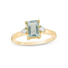 an emerald and diamond ring with two diamonds on the side, set in yellow gold