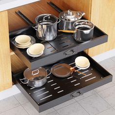 pots and pans are sitting on the shelf in the kitchen drawer, which is open to reveal utensils