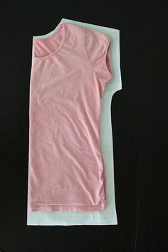 a pink shirt laying on top of a black surface