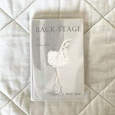 the back - stage book is laying on a quilted bed cover with white sheets