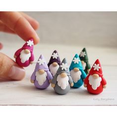 a hand reaching for small toy figurines in the shape of gnomes on a table