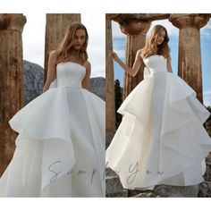 a woman in a white wedding dress standing next to columns