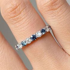 a woman's wedding ring with blue and white stones