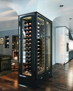 a wine cellar in the middle of a room with wood flooring and white walls