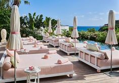 an outdoor lounge area with pink cushions and umbrellas