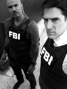 two men in black vests standing next to each other with the words fbi on them