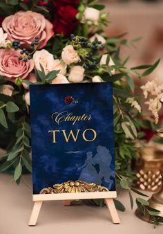 a blue sign sitting on top of a wooden easel next to flowers and candles