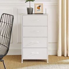 a white chest of drawers sitting next to a chair in a room with a plant on top of it