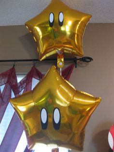 some gold foil balloons are hanging from the ceiling with mickey mouse ears on them,