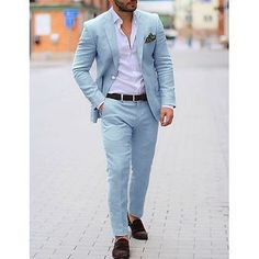 a man in a blue suit walking down the street with his hands in his pockets