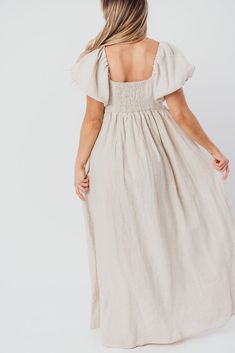 Join us in welcoming the *breathtaking* Candace Maxi Dress to the Worth Collective repertoire - we know you're going to love her! This neutral-hued, 100% linen dress is the epitome of elegance and luxury. Its beautiful neckline frames your decolletage, while the gently puffed sleeves and full skirt accent this gown's exquisite craftmanship. It's the perfect choice for this season's weddings, photo shoots, and other special events! FIT: Runs true to size. Empire waist and smocked bodice will accommodate early-to-mid maternity baby bumps. Long length (top of foot for our 5'7" models). MATERIAL: 100% Linen. GARMENT DETAILS: Short-sleeved maxi dress with an empire waist and full, flowing skirt. Features a square neckline, puffed sleeves that can be worn on or off the shoulder, and a structured Linen Maxi Dress With Smocked Back And Fitted Style, Fitted Linen Maxi Dress With Smocked Back, Linen Vacation Dress With Smocked Back, Spring Linen Dress With Smocked Back, Flowy Linen Midi Dress For Brunch, Chic Flowy Linen Dress, Spring Cream Linen Maxi Dress, Chic Linen Maxi Dress With Smocked Back, Flowy Linen Dress For Brunch