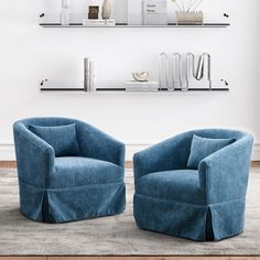 two blue chairs sitting next to each other on top of a carpeted floor in front of a white wall