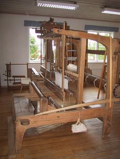 an old weaving machine is in the middle of a room with wooden floors and windows