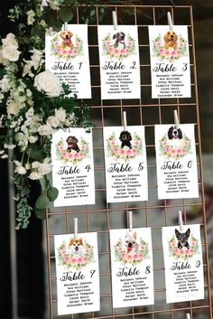 wedding seating cards with dogs on them are hanging from a metal rack and surrounded by flowers