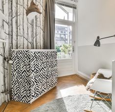 a white and black patterned cabinet next to a window in a room with wooden floors