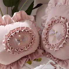 two pink pillows with ruffled edges and an embroidered heart on the center, surrounded by other decorative items