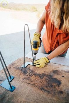 a woman using a driller on a piece of wood that is being used as a table