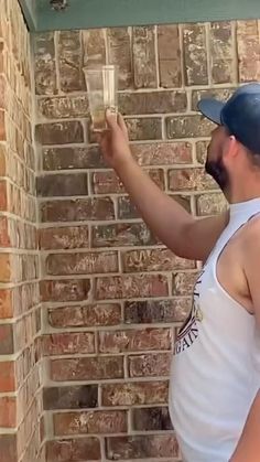 a man is painting a brick wall with a paint roller in front of his face