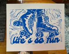 a hand holding up a blue and white card with an image of roller skates