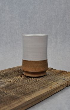 a white and brown cup sitting on top of a wooden board