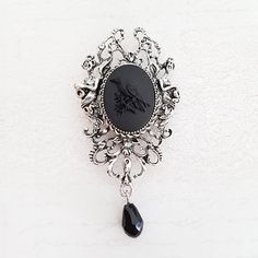 Antique silver Gothic style Victorian inspired large cameo 2 in 1 necklace brooch in black. The cameo is completely black, with detailed black raven, and is set in an ornate antique silver plated setting on a long antique silver plated chain. Underneath is a faceted black glass teardrop bead. The brooch can be easily threaded onto the chain to make a necklace. The setting is 3 inches (75 mm) from top to bottom, including the bead, and has a brooch fastening on the back, the matching chain has a Gothic Brooch Jewelry Gift, Black Gothic Jewelry Brooch, Gothic Formal Jewelry Brooch, Black Gothic Brooch Jewelry, Black Gothic Brooch, Victorian Black Brooches As Gift, Antique Black Brooch For Gift, Victorian Black Brooches For Gifts, Victorian Style Black Brooches For Gifts