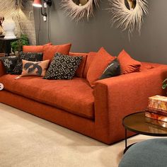 a living room with orange couches and decorative mirrors on the wall above them,