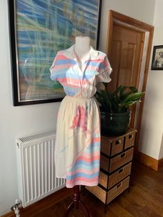 A totally gorgeous vintage summer dress in perfect pastels and white. Classic in shape and bold in design this piece feels timeless and contemporary--throw it on with white trainers, chunky sandals, kitten heels, or boots. You could style this so many ways from cocktails to beach cover up. Marked as a UK size 14, but as it's vintage it will be more like a modern 12--please do check the measurements in the photos. In excellent vintage condition, ready to be worn and loved again!  All items listed in Attic 1 Shop are vintage and pre-owned/pre-worn unless explicitly stated in the listing. Please be aware that this means items are not in brand new condition and you must read item descriptions thoroughly to ensure you are happy with the item before purchasing. Vintage clothing may not be labell Retro V-neck Midi Dress For Summer, Vintage V-neck Dress For Summer Daywear, Multicolor Summer Shirt Dress For Beach, Multicolor Shirt Dress For Summer Daywear, Summer Midi Dress For Daywear, Beach Summer Midi-length Shirt Dress, Beach Summer Midi Length Shirt Dress, Summer White Vintage Dress, Feminine Summer Shirt Dress For Day Out