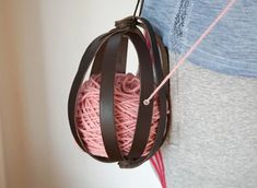 a ball of yarn hanging from a hook on a wall with a woman's shirt in the background