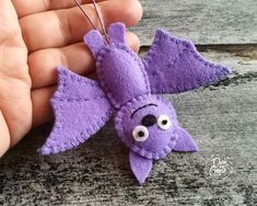 a hand holding a purple felt bat ornament