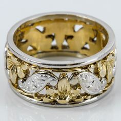 a close up of a wedding ring on a white surface with gold leaves and flowers